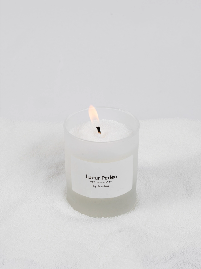 Bougie Lueur Perlée présentée dans contenant en verre givré blanc.