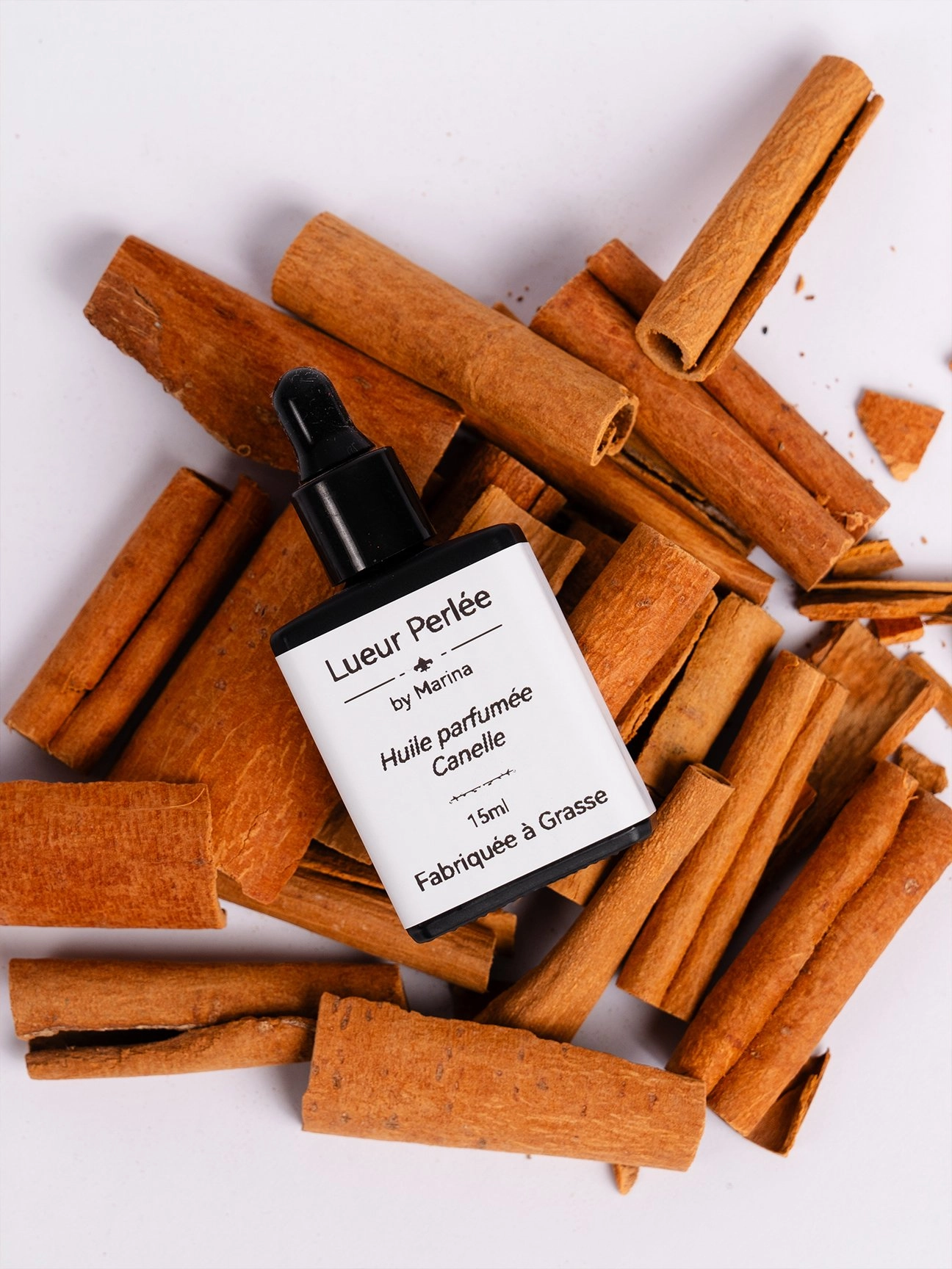 Huile parfumée pour bougie en perle de cire sur lit de cannelle.