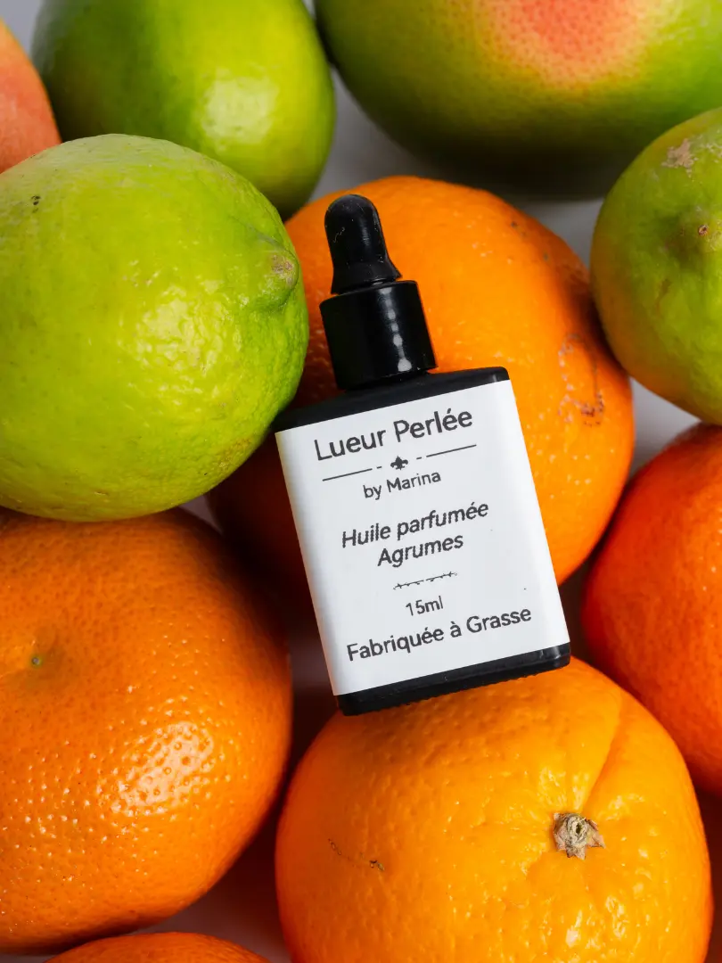 Huile parfumée pour bougie perlée agrumes sur lit de citron et d'oranges.