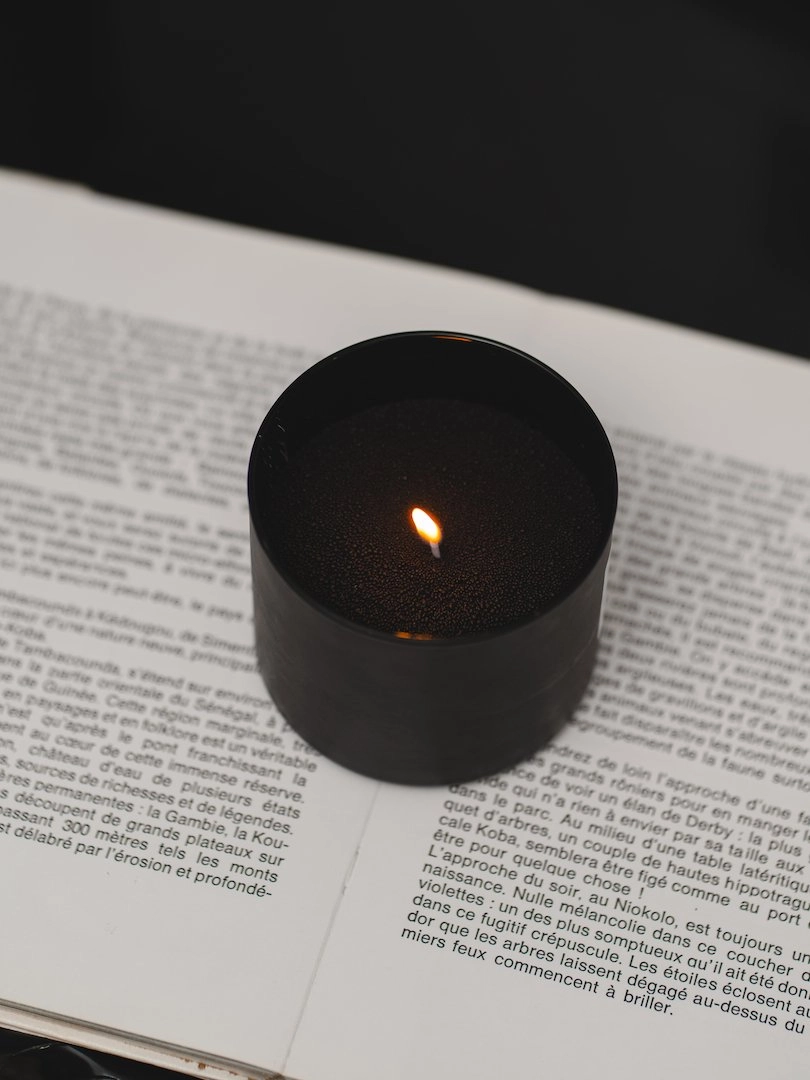 Bougie Lueur Perlée en perle de cire végétale allumée sur un livre.